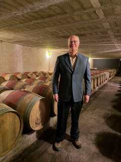 Brian in a Bordeaux barrel cellar among rows of aging oak barrels
